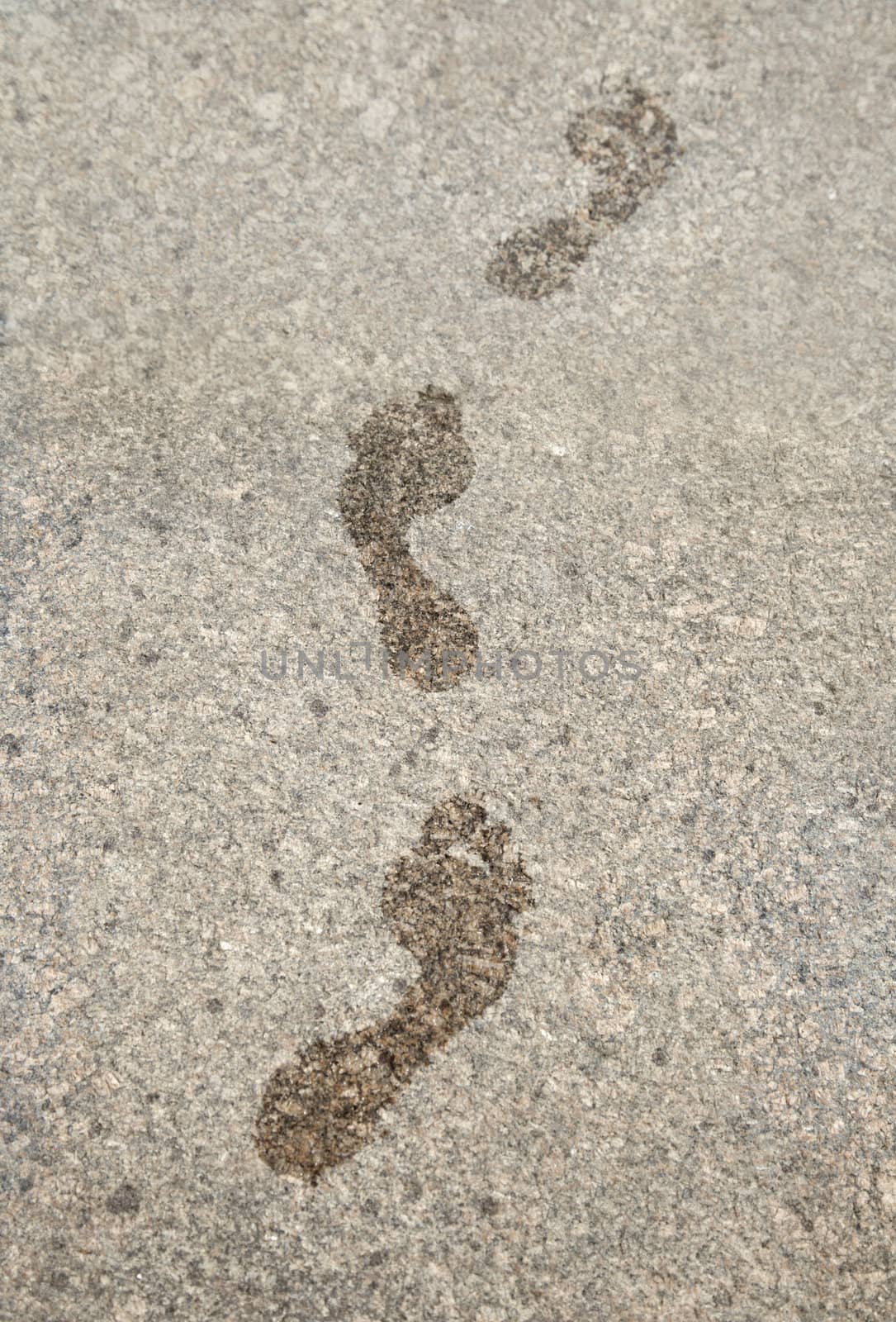 Wet prints of bare feet on granite