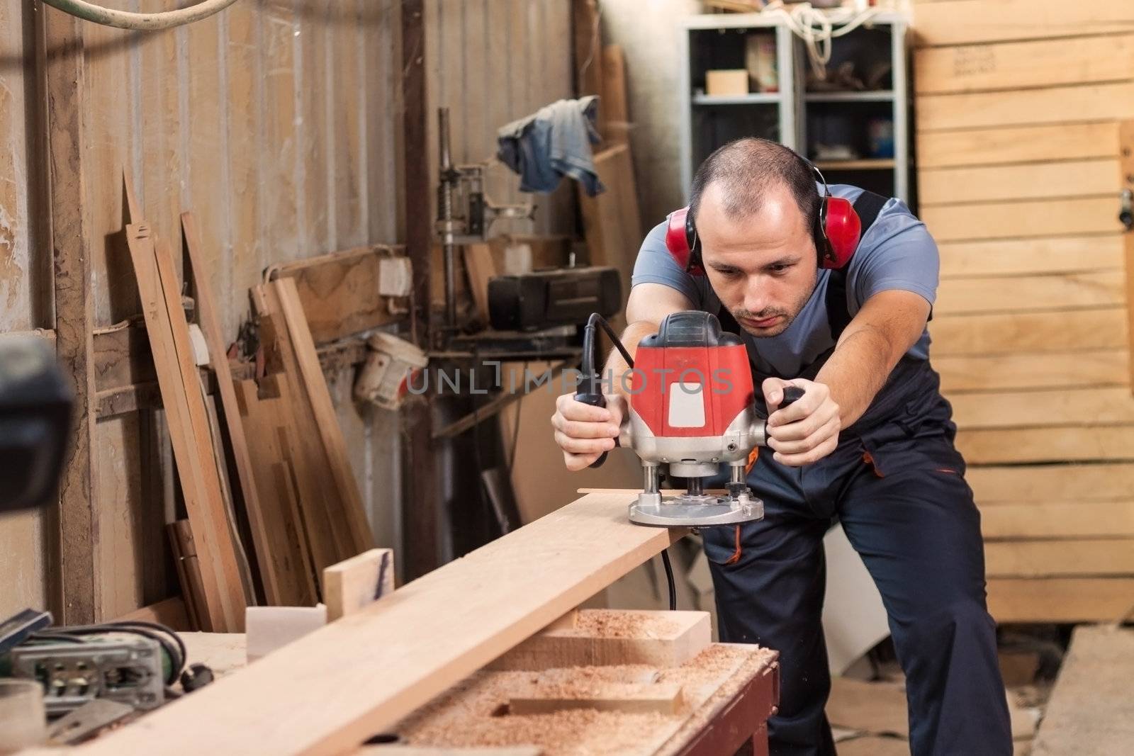 Carpenter with an electric router, horizontal shot