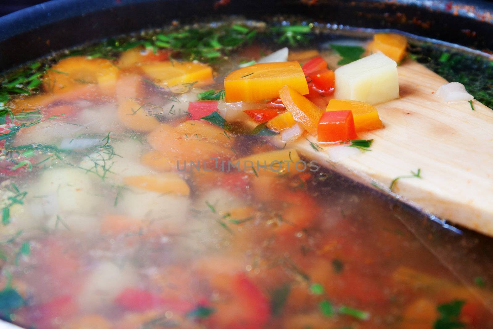 Vegetable soup in a pot with wooden spoon