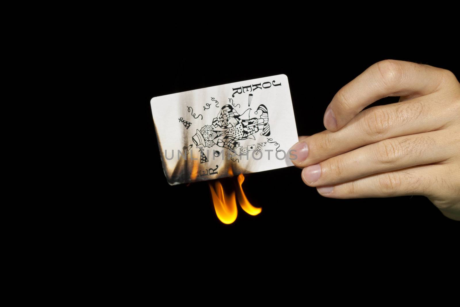 A man burns a joker card.