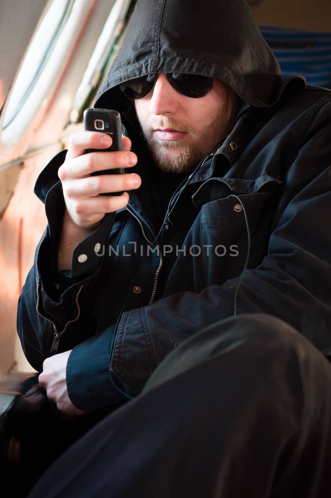 Hooded man looking at his cellular phone in an old airplane