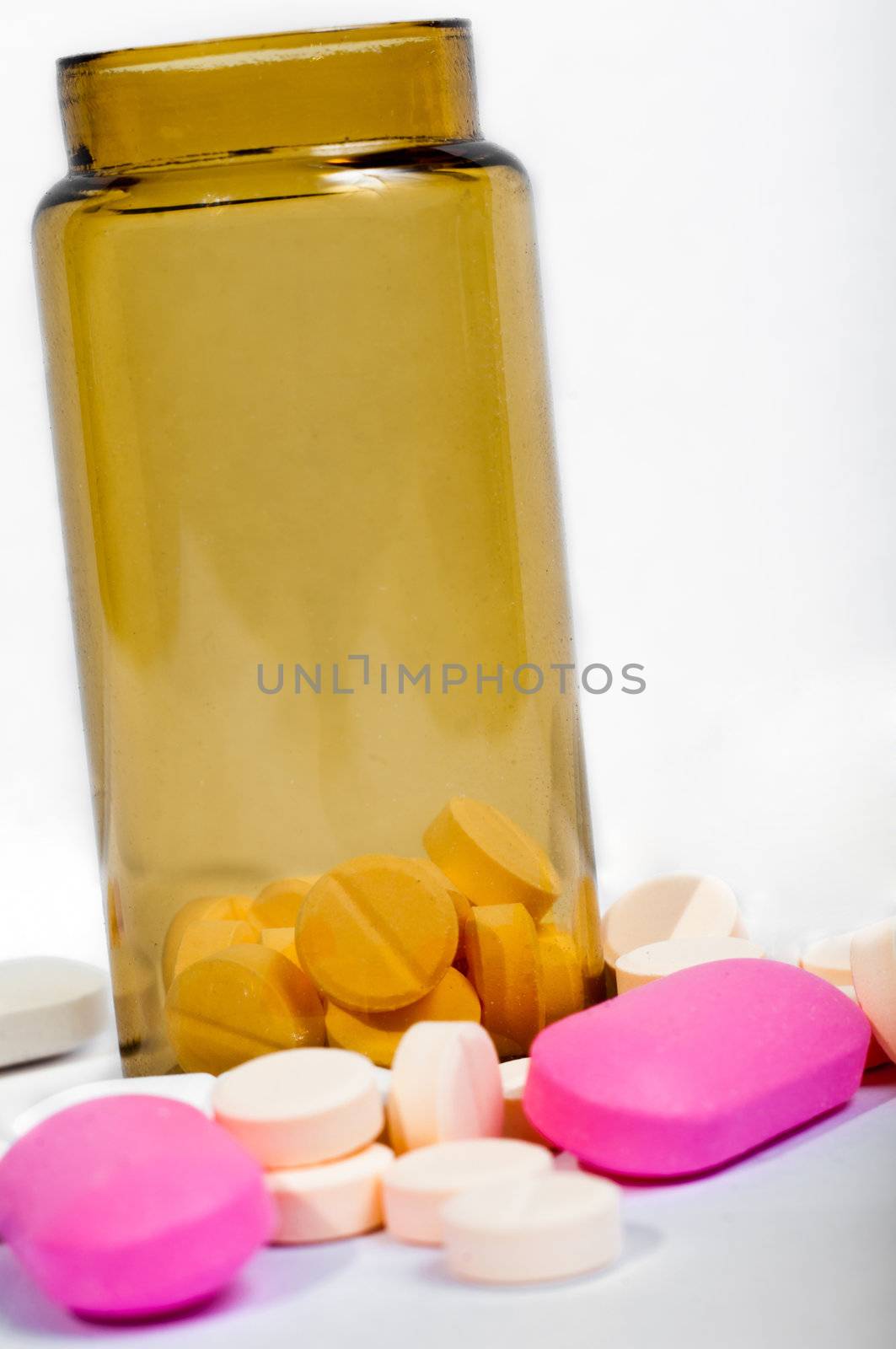 Medicine bottle with purple and yellow pills against white isolated background