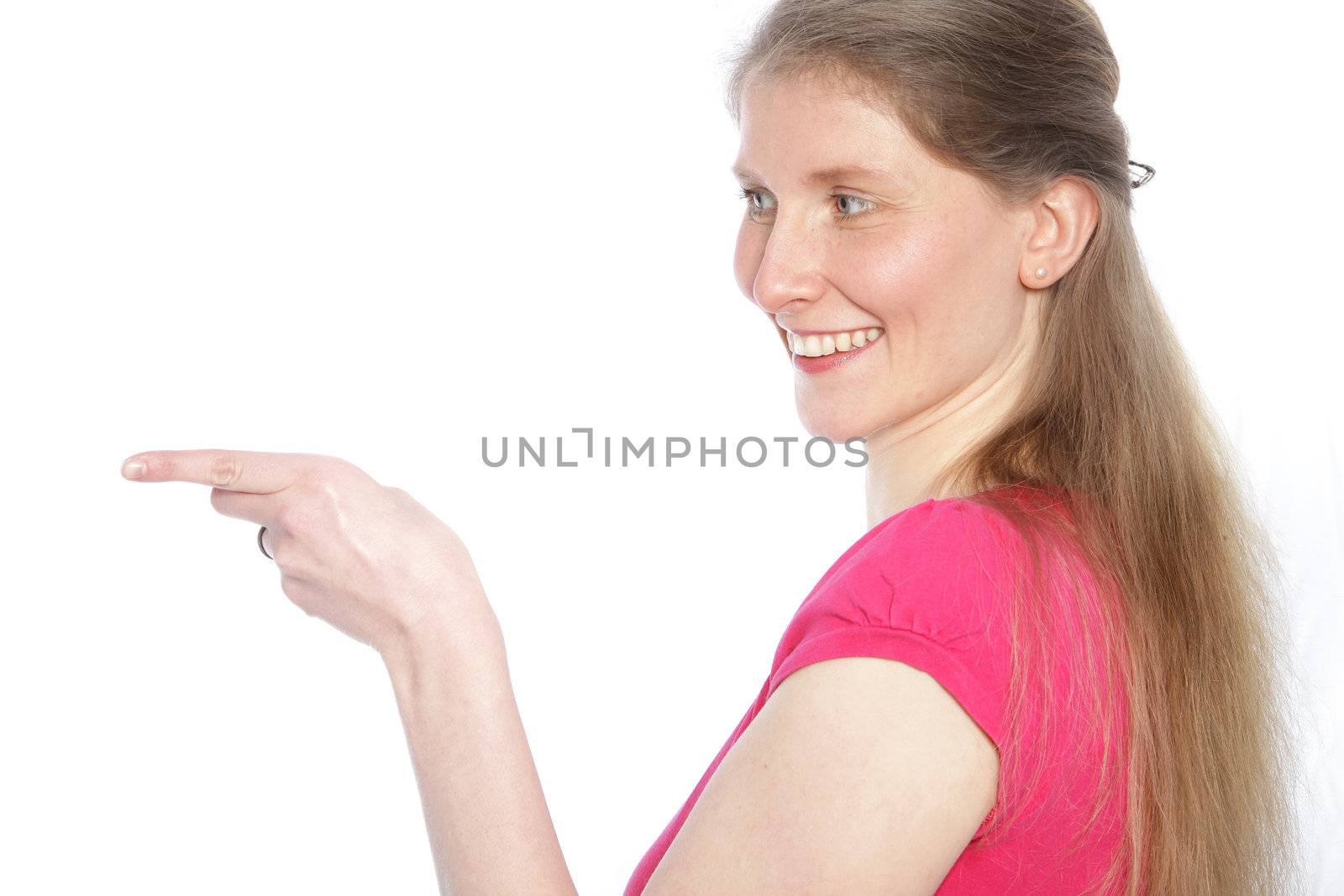 Smiling attractive middle-aged woman with long blond hair standing sideways pointing with her finger to the left of the frame isolated on white