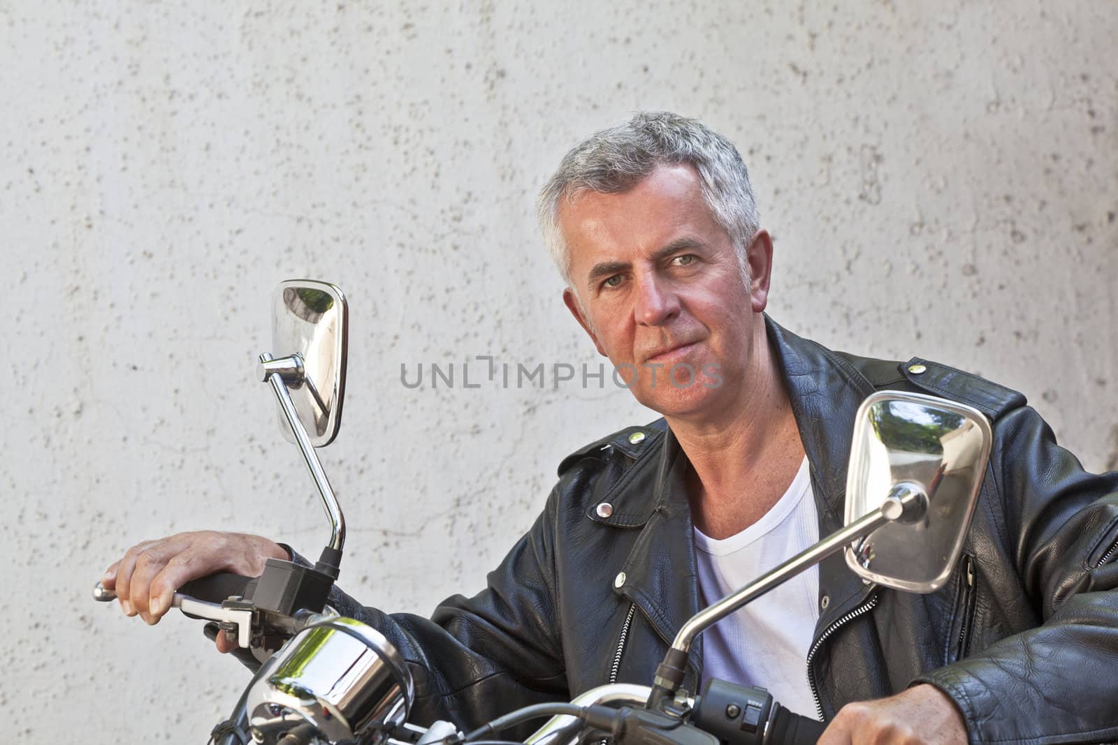 Capture of a Caucasian motorbiker in casual attire and relaxed expression looking into lens sat on a red cruiser. Generic shot location was Bombay India