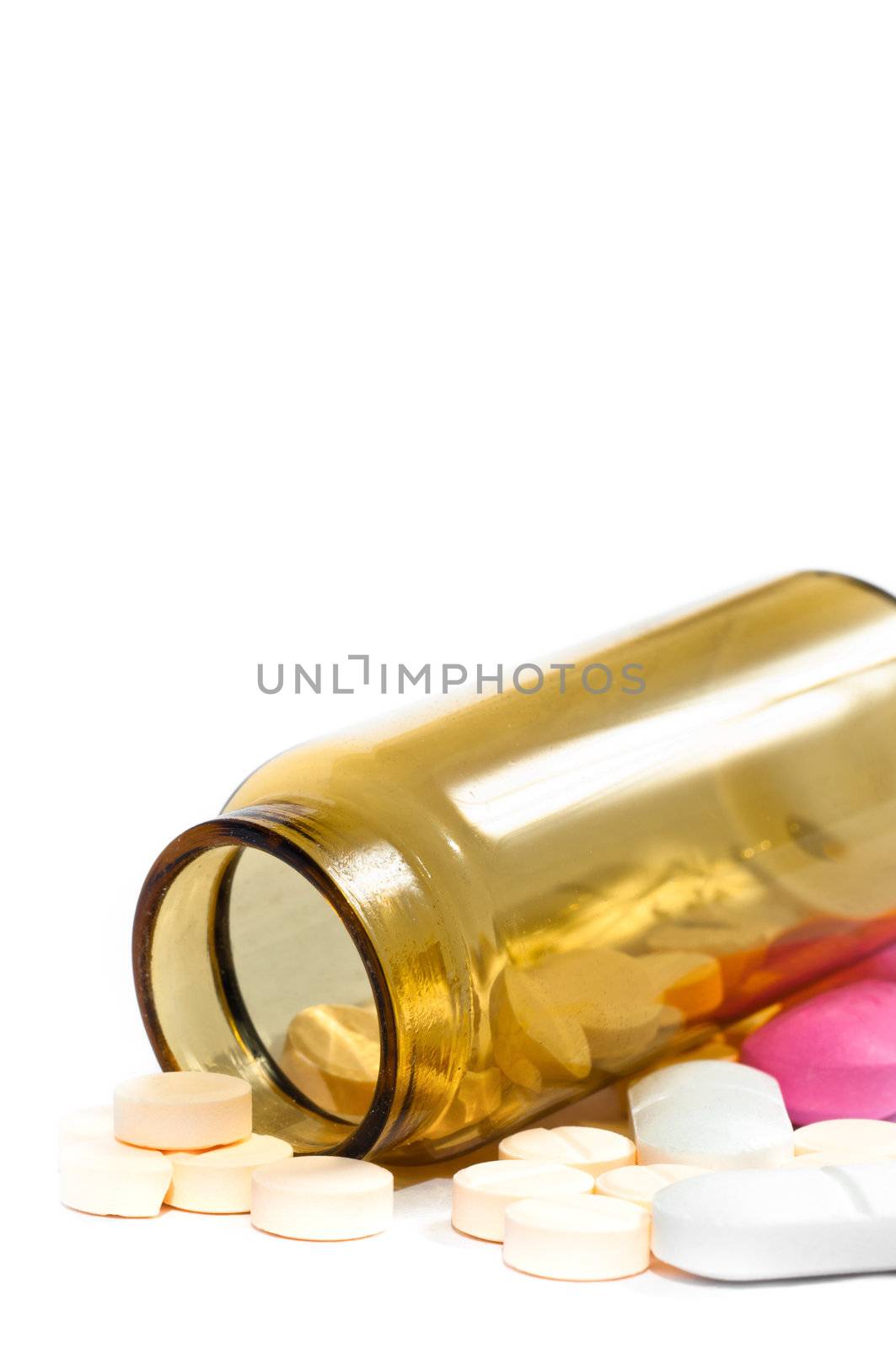 Medicine bottle with purple and yellow pills against white isolated background