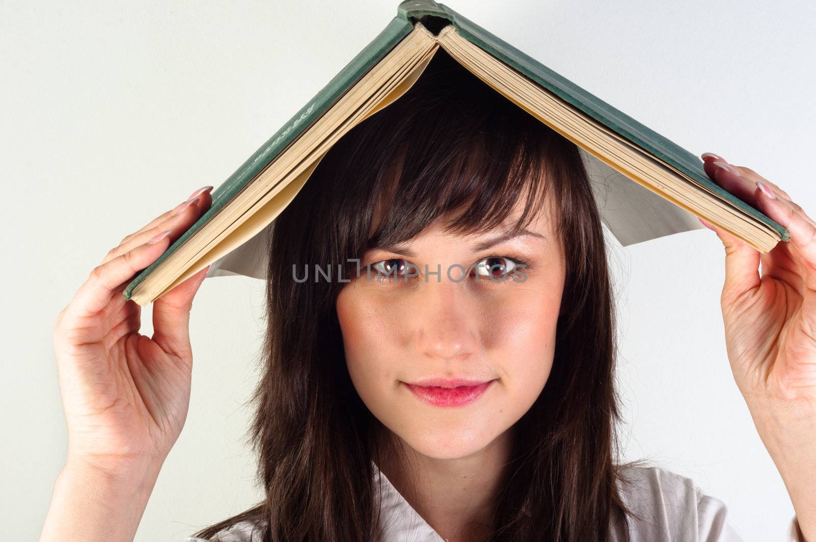 Beautiful young girl hiding under book