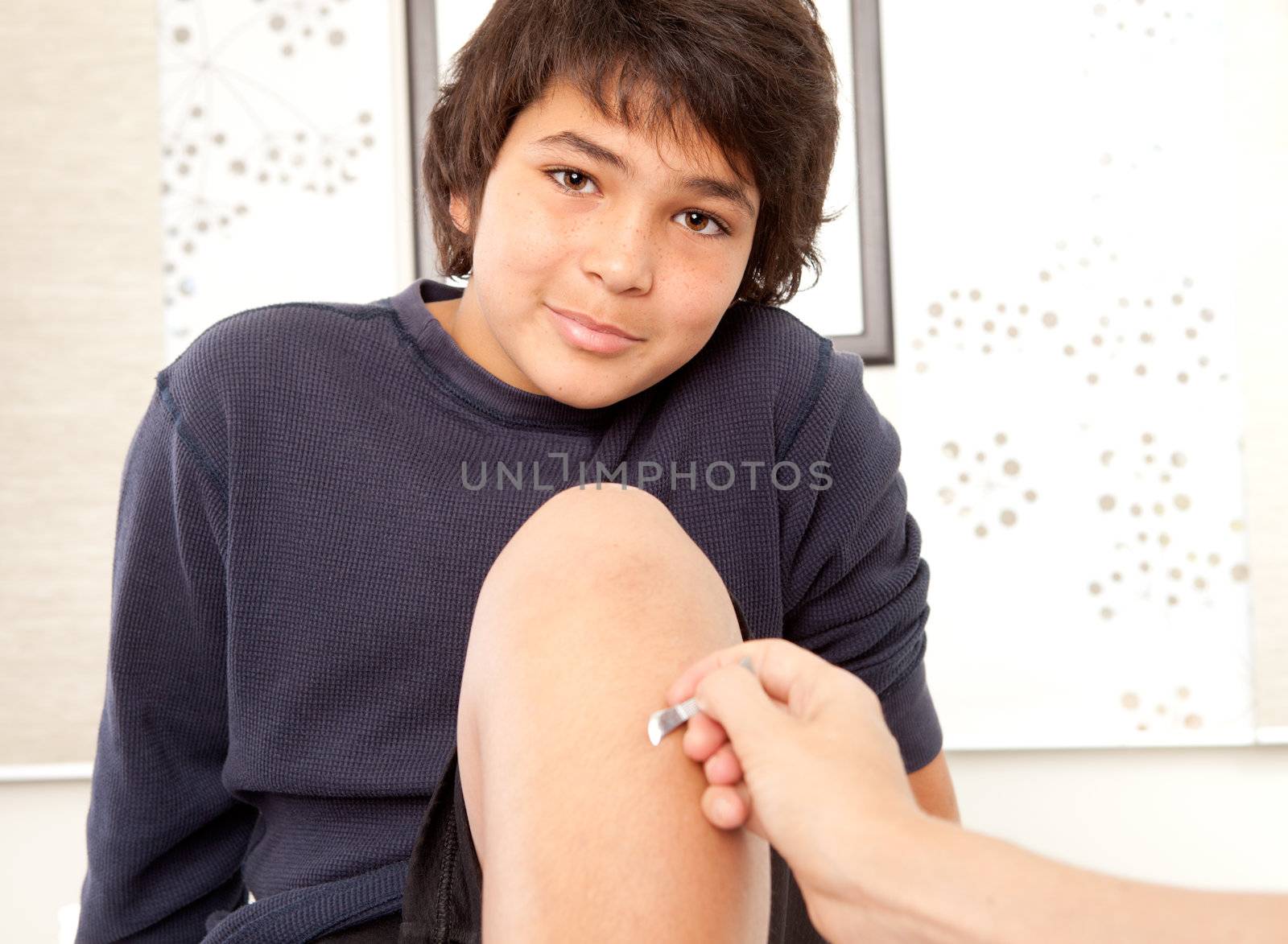 Portrait of a happy young male receiving Shonishin acupuncture on the leg with a choto tool.  Shallow depth of field, focus on eyes.