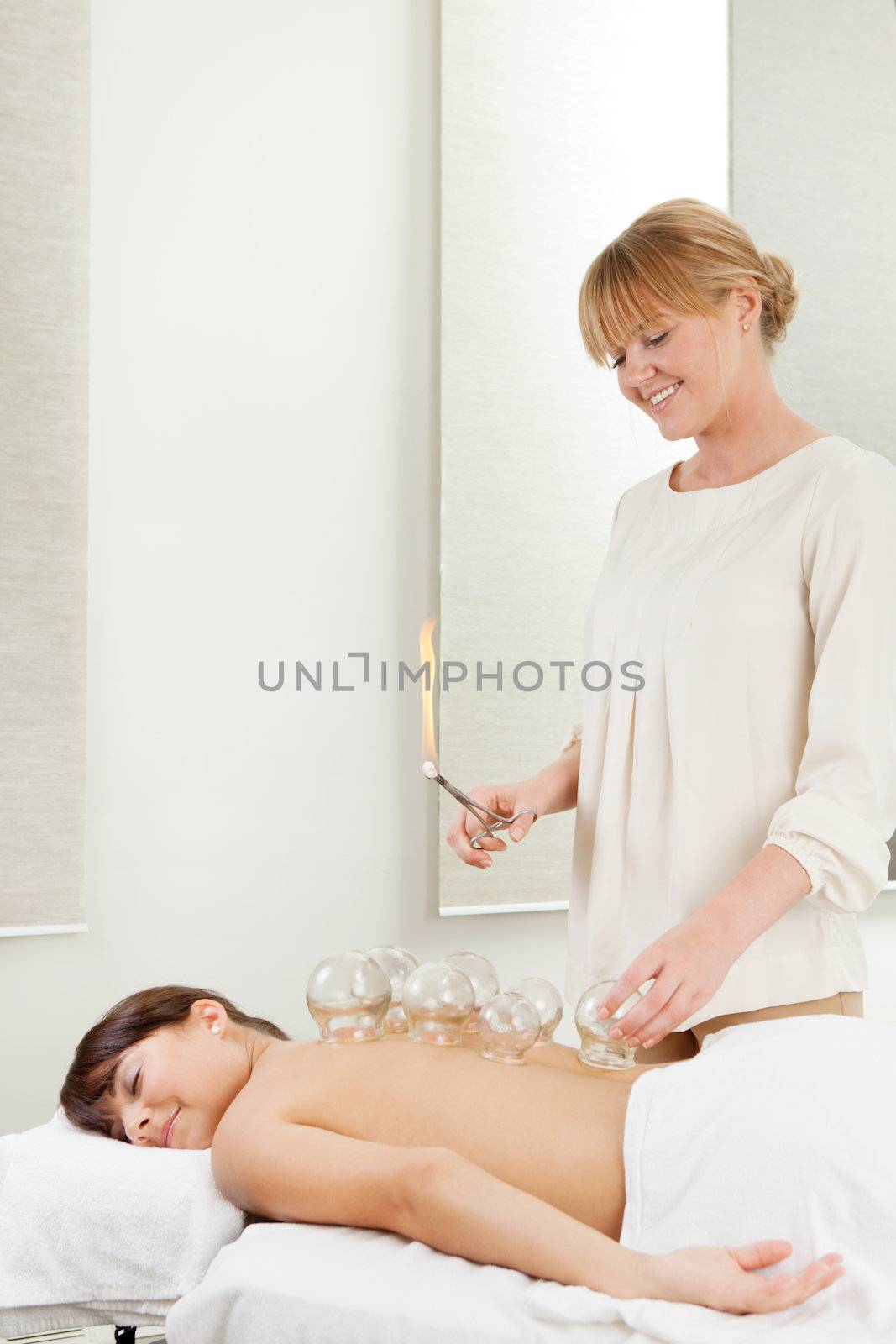 Young relaxed woman receiving fire cupping from a professional acupuncture therapist