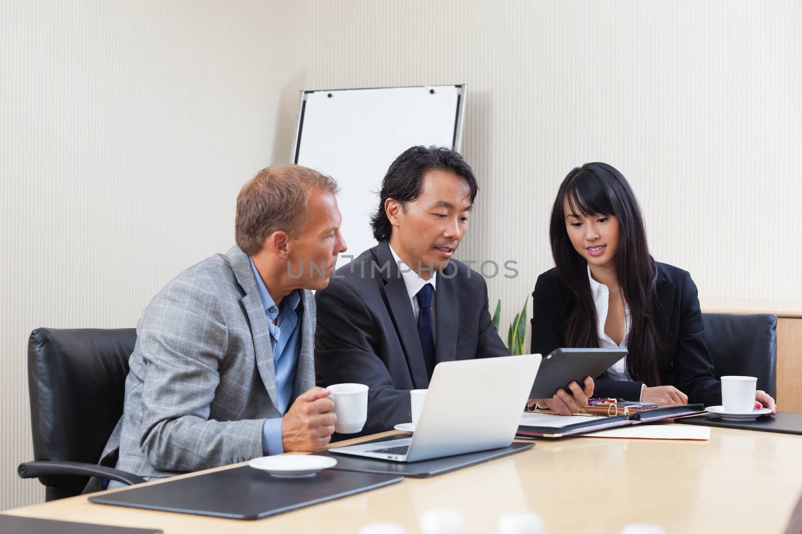 Business people using tablet in meeting by leaf