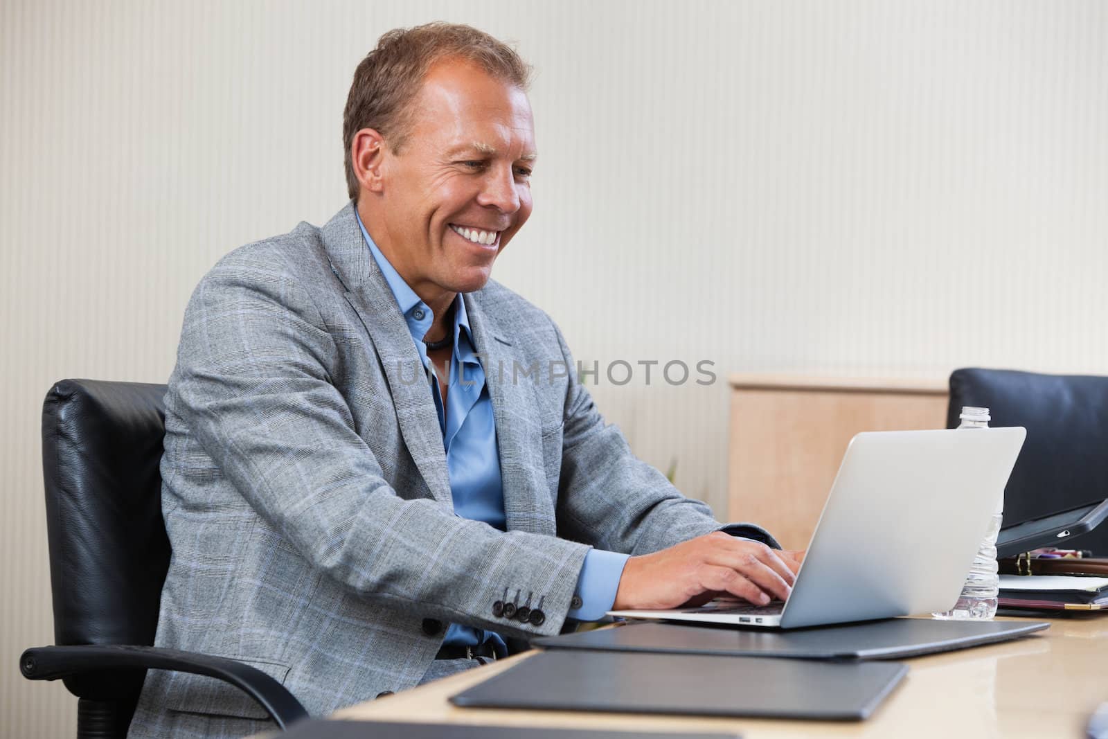 Cheerful businessman working on laptop by leaf