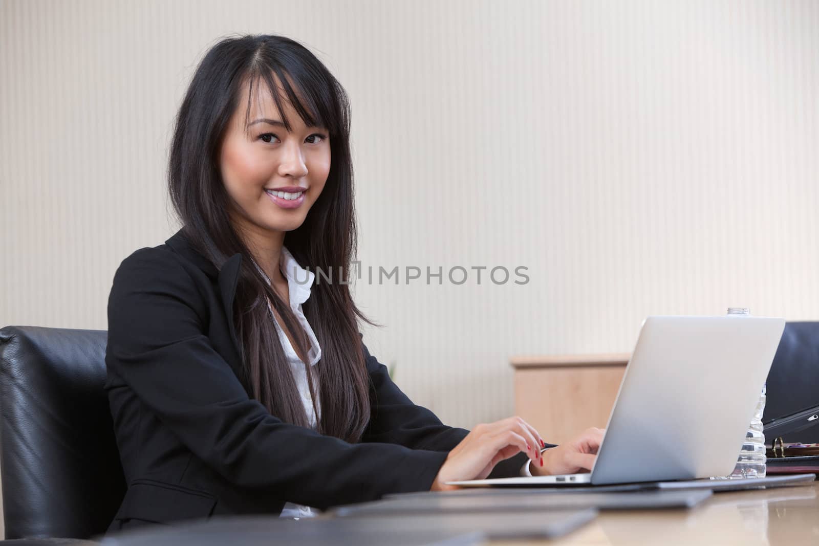 Young business woman working on laptop by leaf