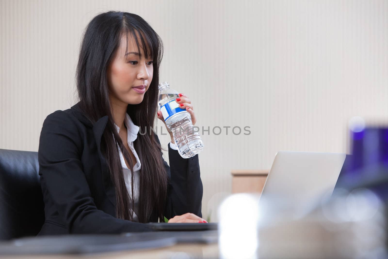 Businesswoman drinking water at work by leaf