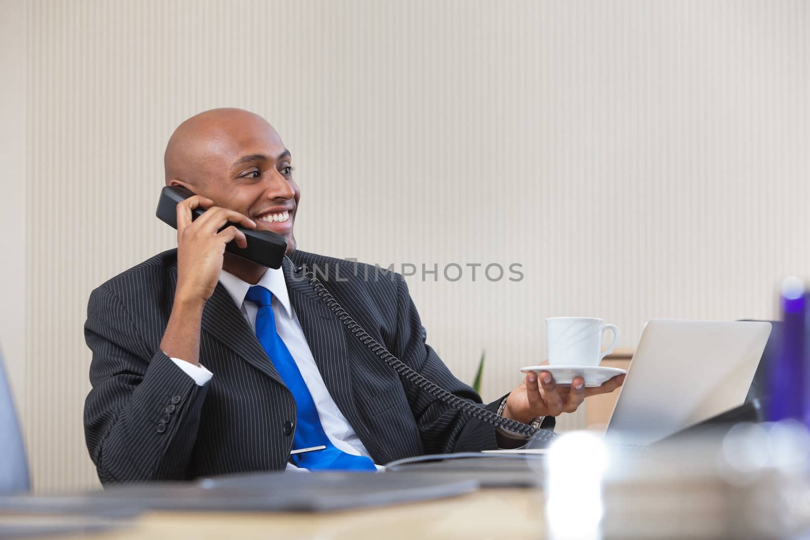 Businessman talking on telephone while having tea by leaf