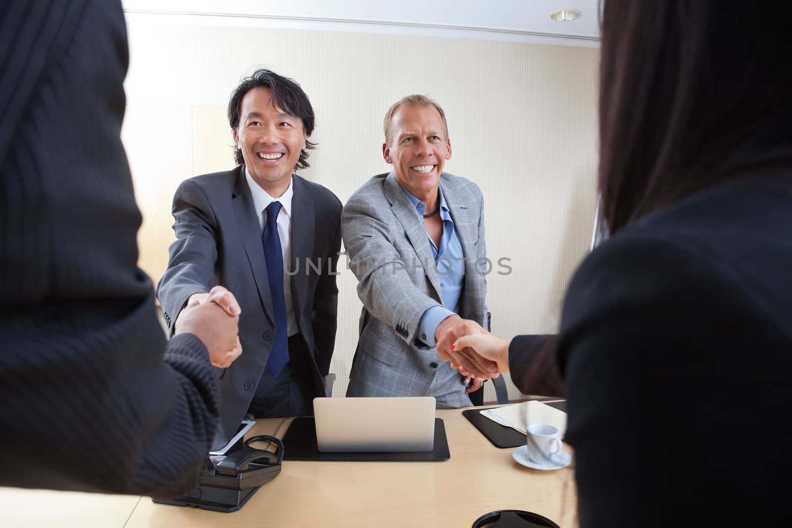 Business people shaking hands by leaf