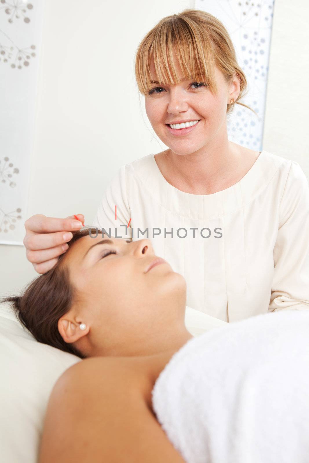 Portrait of a professional acupuncturist stimulating a needle in the face of a patient