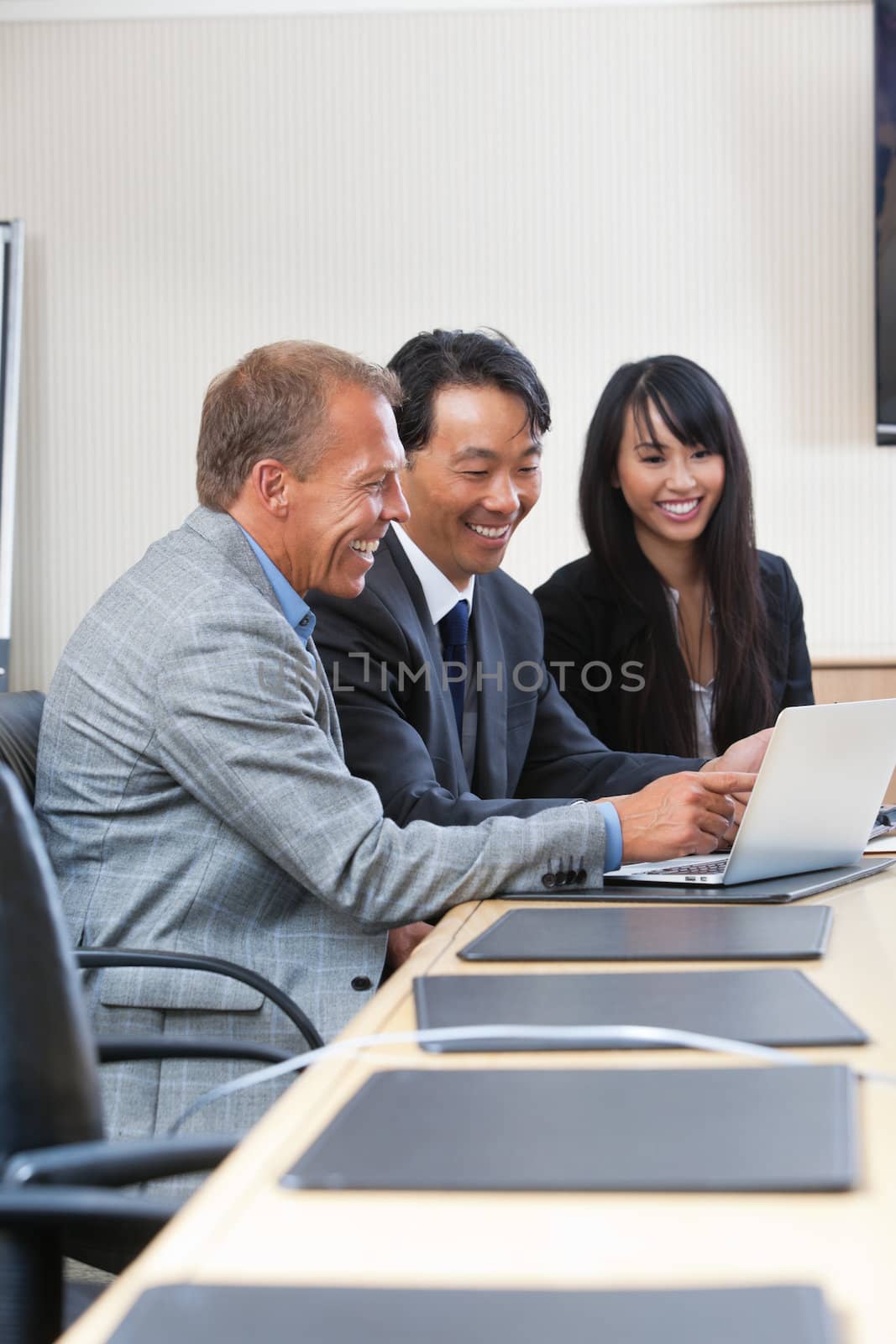 Smiling business people laughing while looking at laptop