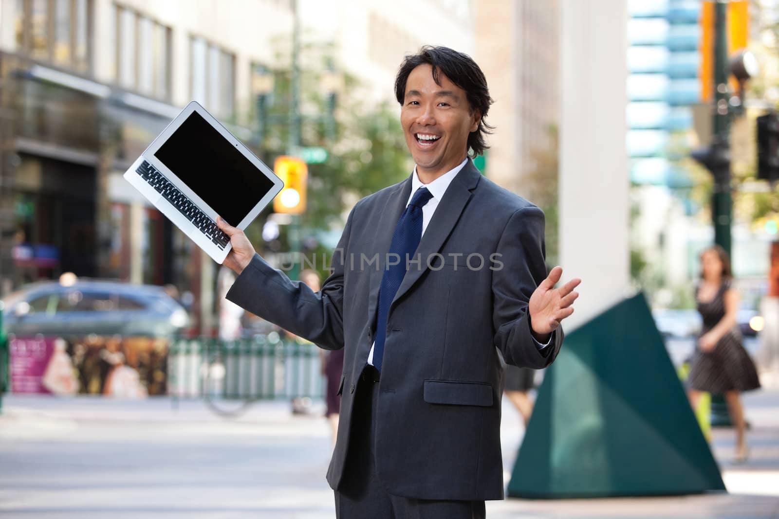 Businessman holding laptop and laughing by leaf