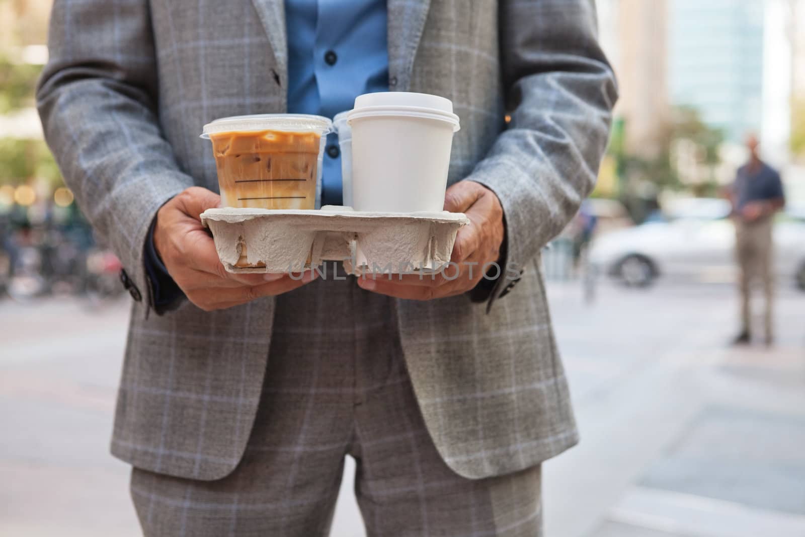 Businessman holding takeaway coffee cups by leaf