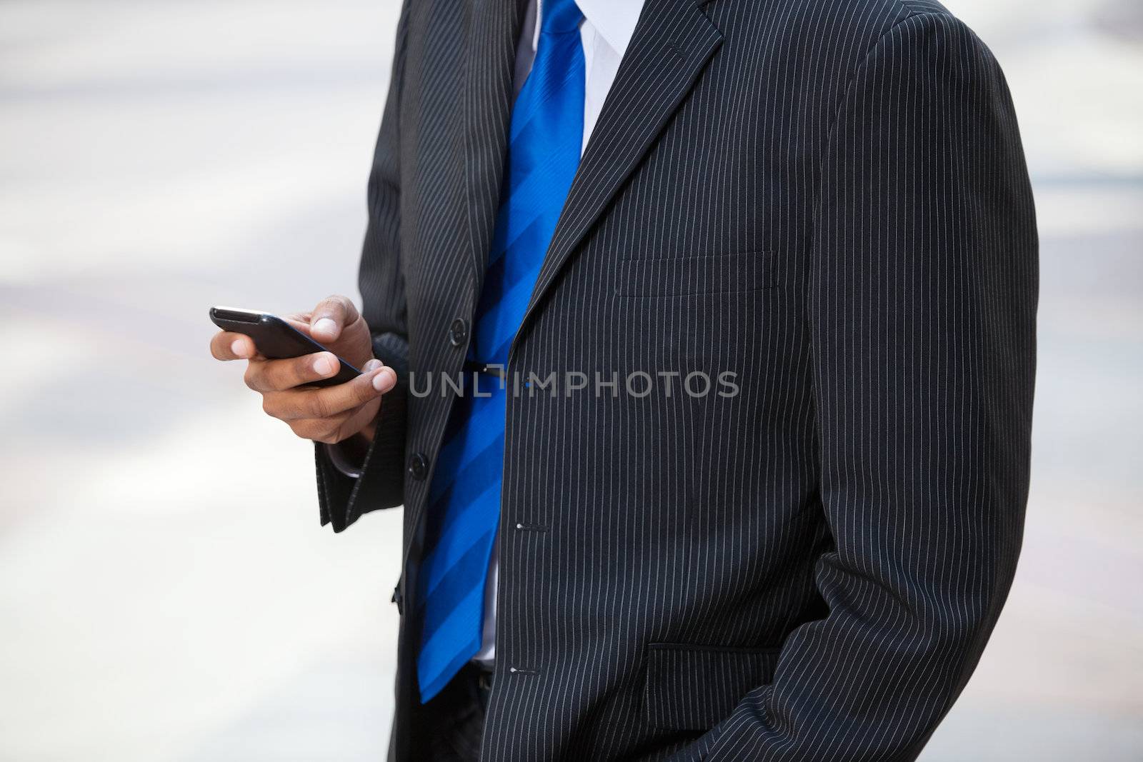 Businessman using cell phone by leaf