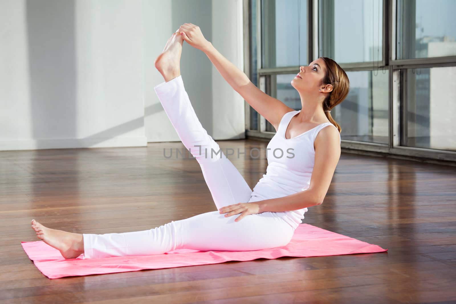 Full length of a young woman doing yoga exercise called Heron Pose at gym