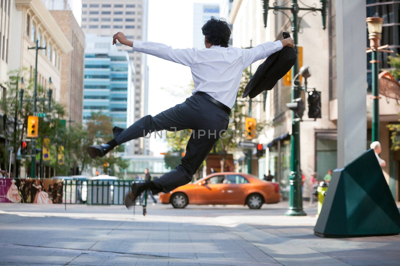 Rear view of business man jumping in air and kicking heals