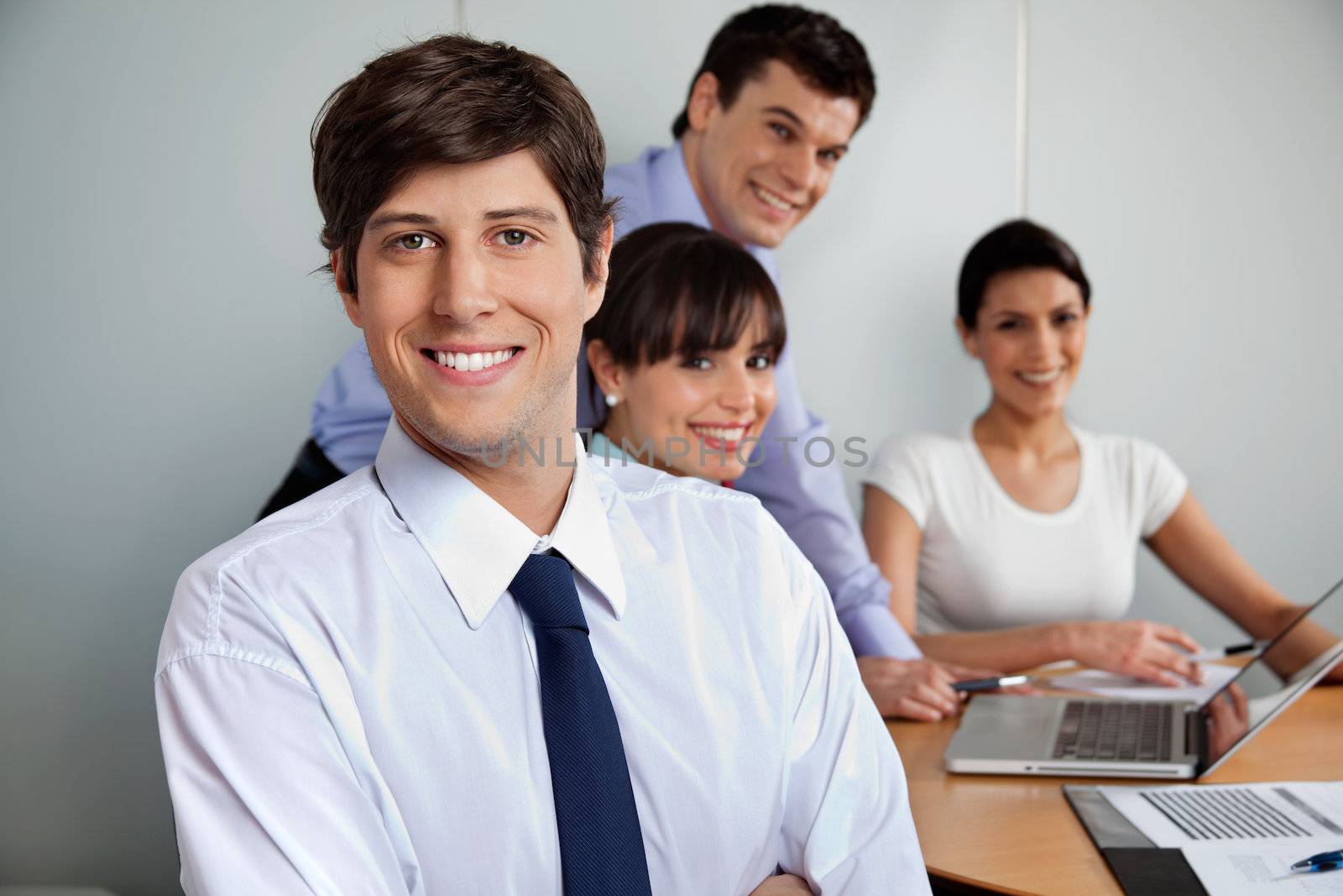 Portrait of handsome businessman smiling with team working in background