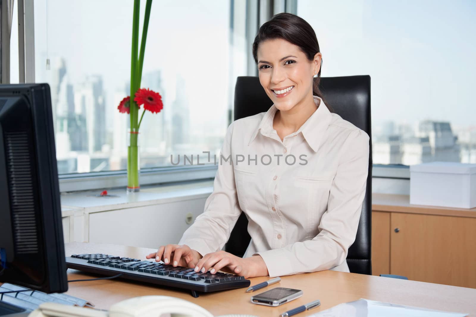 Portrait of smiling female entrepreneur working on computer in office