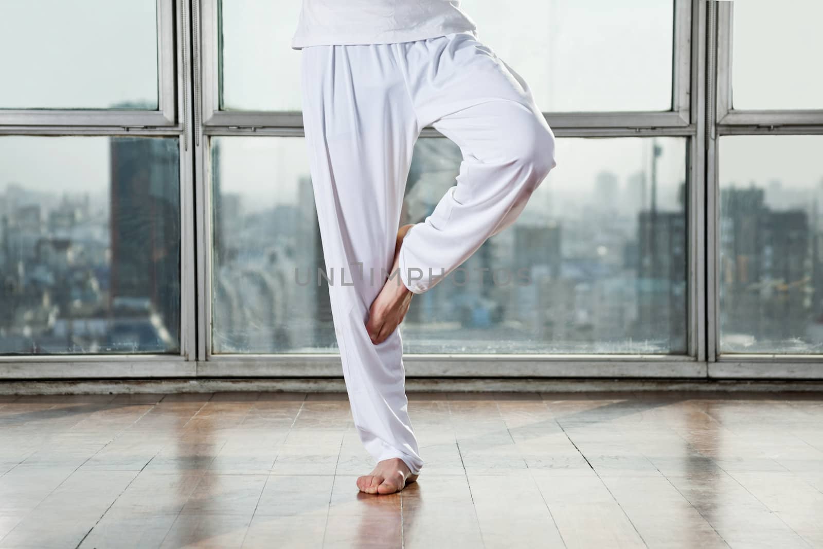 Low section of a man practicing yoga called Tree Pose at gym