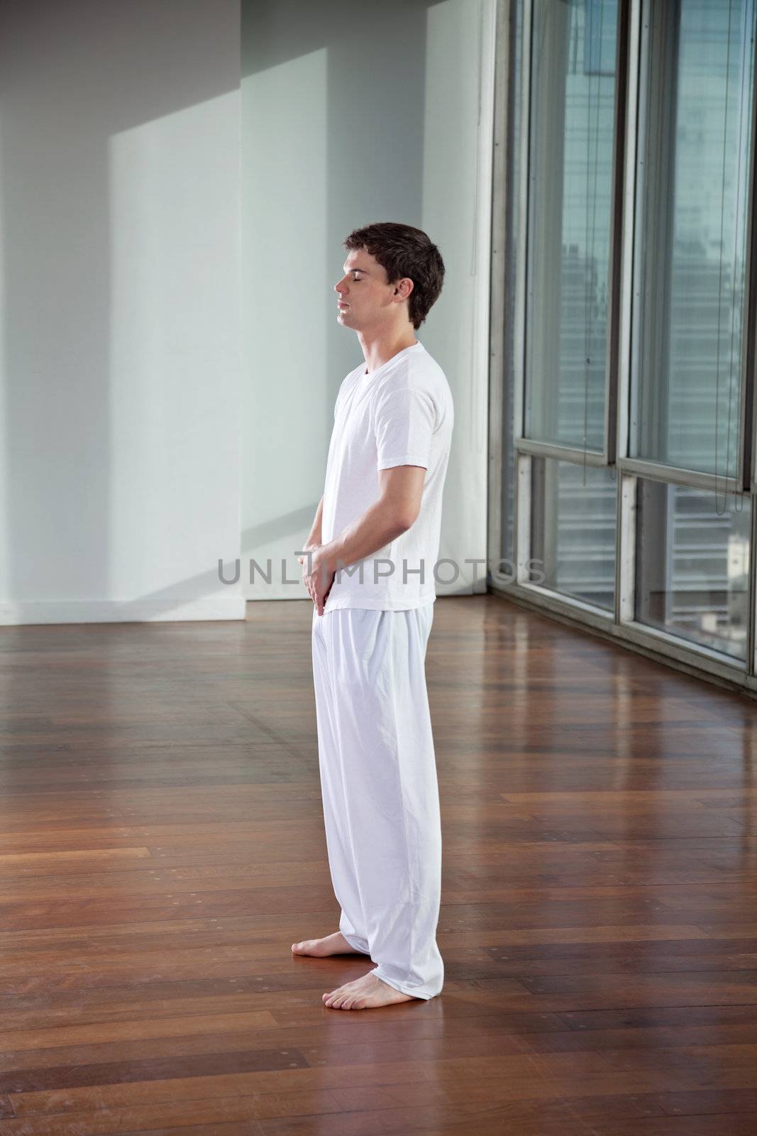 Side view of a young man exercising with eyes closed at gym