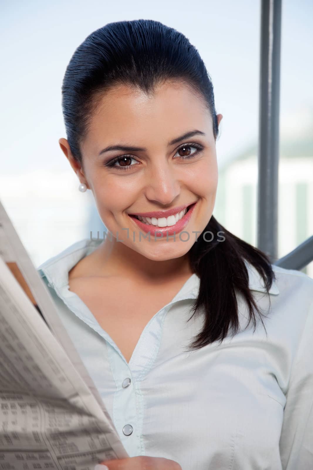 Portrait of happy female executive holding newspaper