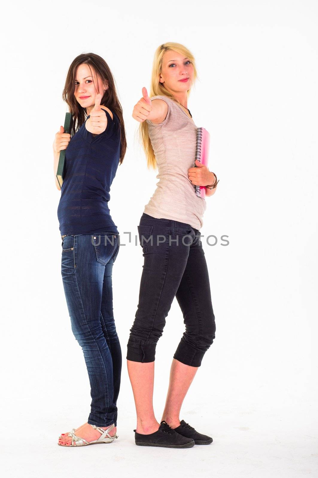 Two beautiful student girls showing thumbs up against white background
