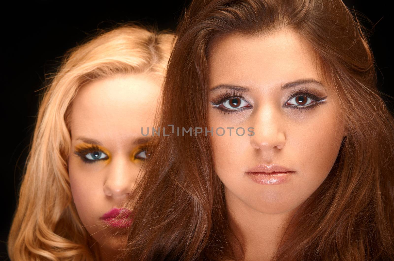 Closeup photo of two young girls in the studio against dark background