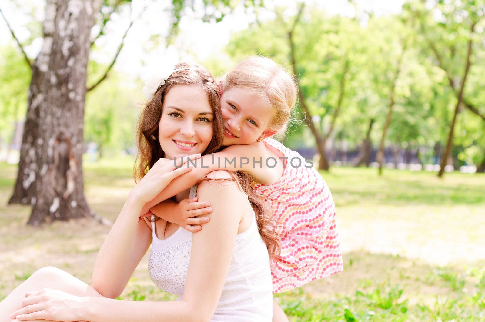 mother and daughter sitting together on the grass by adam121