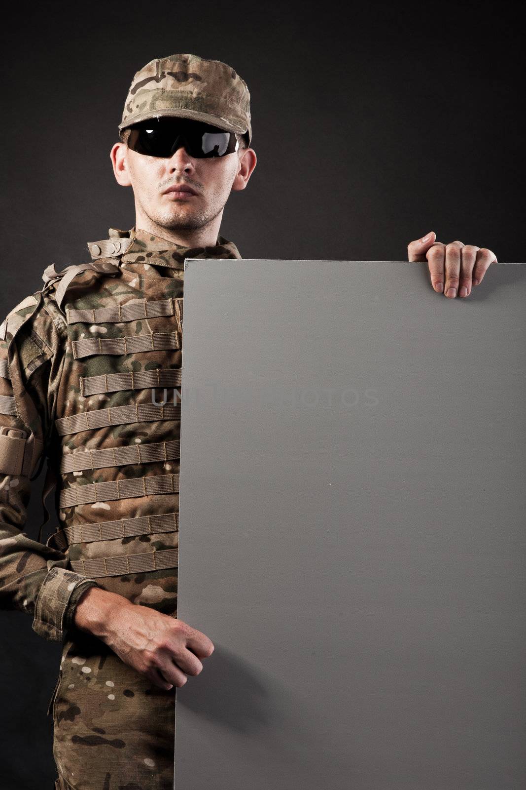 Modern soldier is holding a poster with smoke isolarted on black background