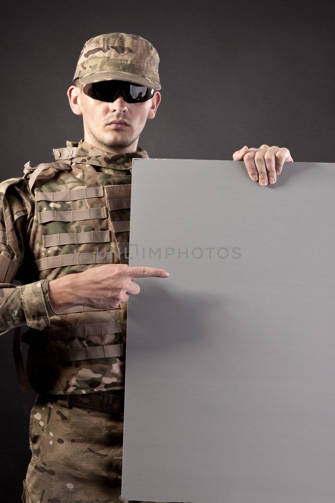 Modern soldier is holding a poster isolarted on black background