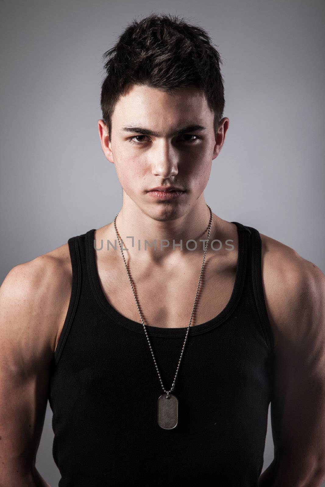 A good looking, muscular built, man on a black background with dog tags.