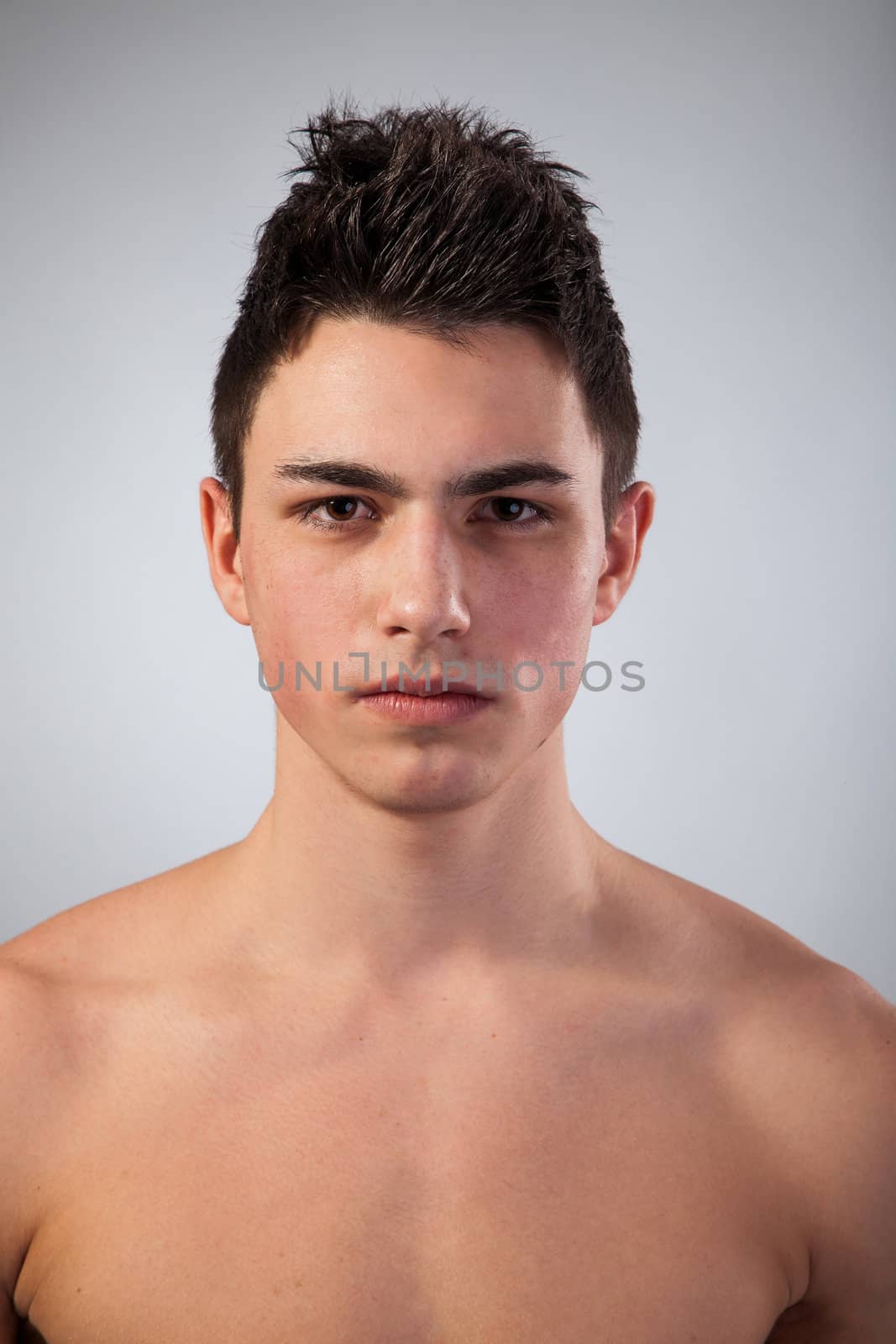 Handsome face of a young man. Isolated on grey background.