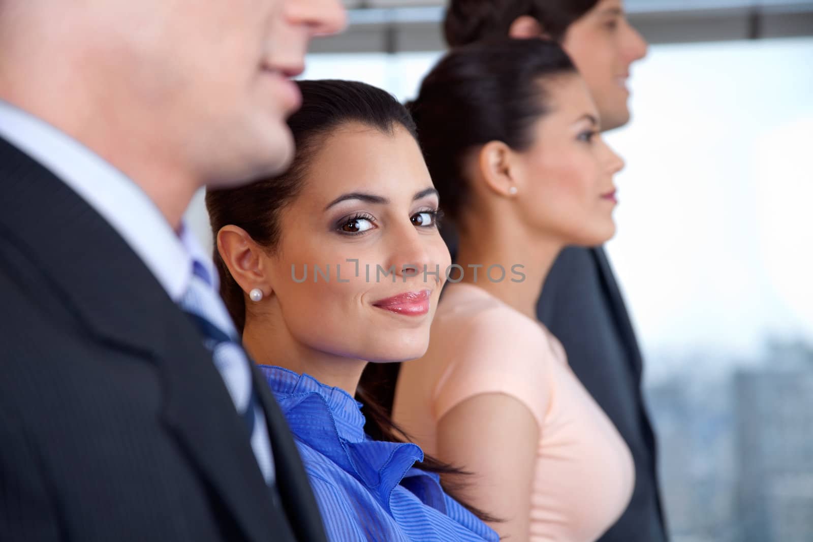 Portrait of smart smiling businesswoman with colleagues standing in a row