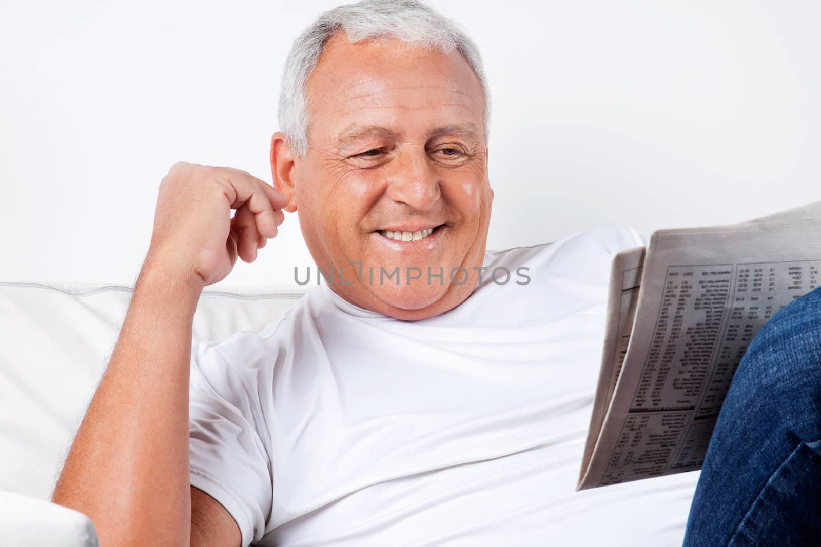 Senior Man Reading Newspaper At Home by leaf