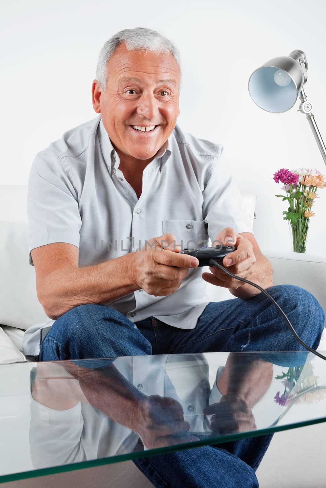 Happy senior man playing video game at home