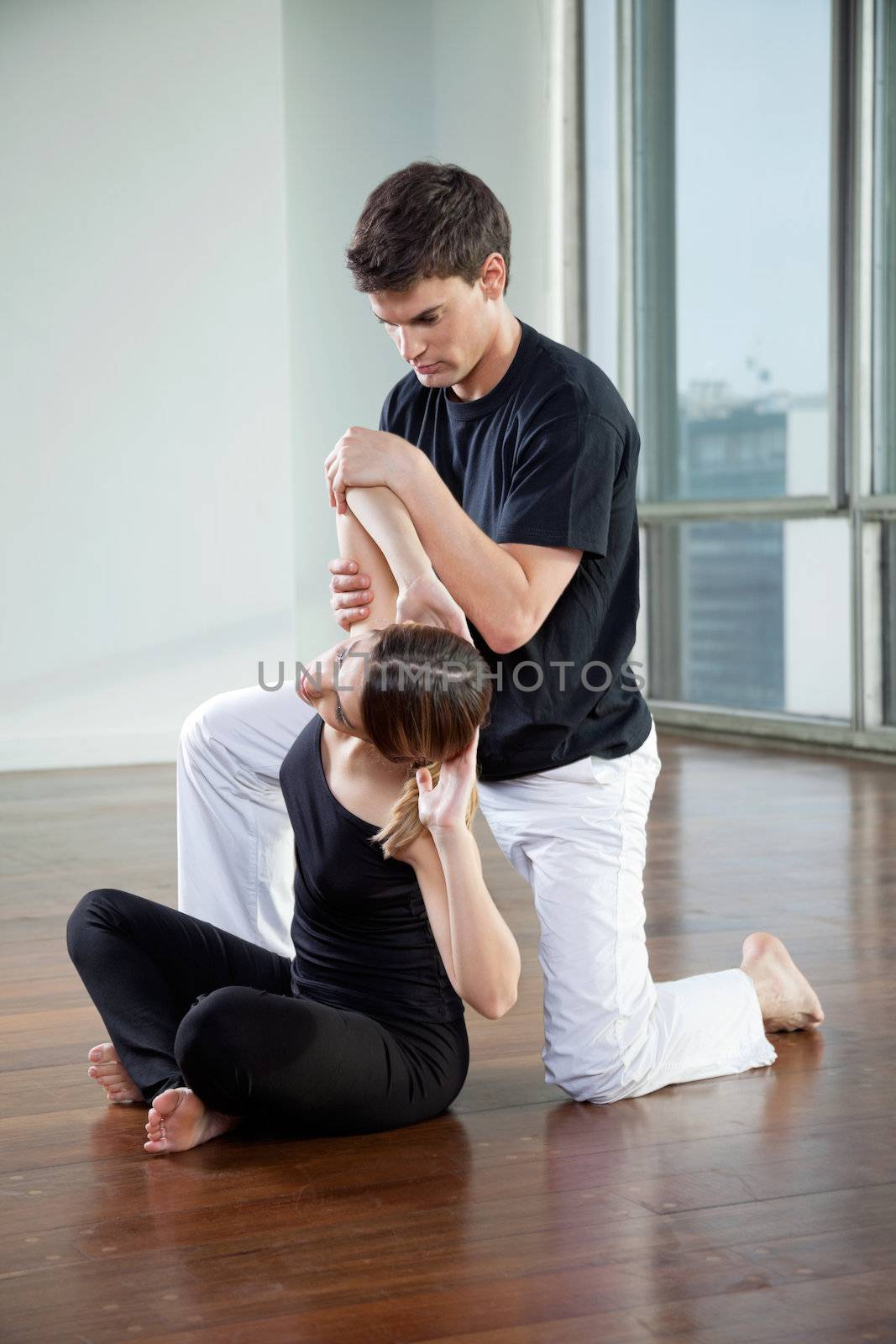 Instructor Helping Woman In Yoga Exercise by leaf