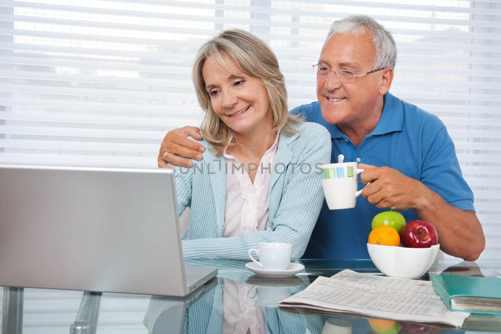 Happy couple using laptop while having breakfast