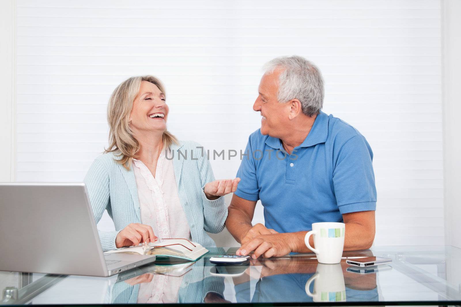 Happy couple at dining table working on laptop on house finance