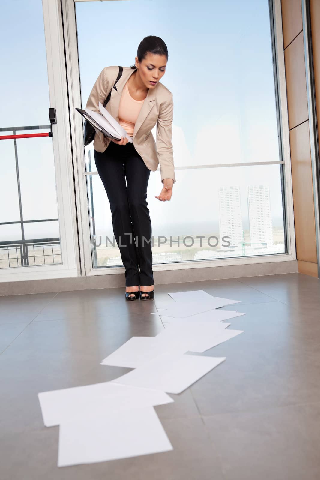 Beautiful business woman bending down to collect scattered papers on floor