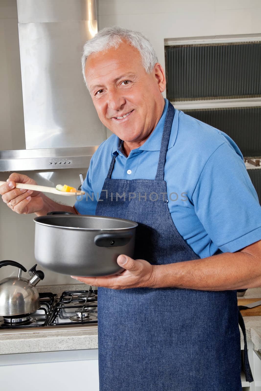 Portrait of smiling senior man holding spoon to taste food