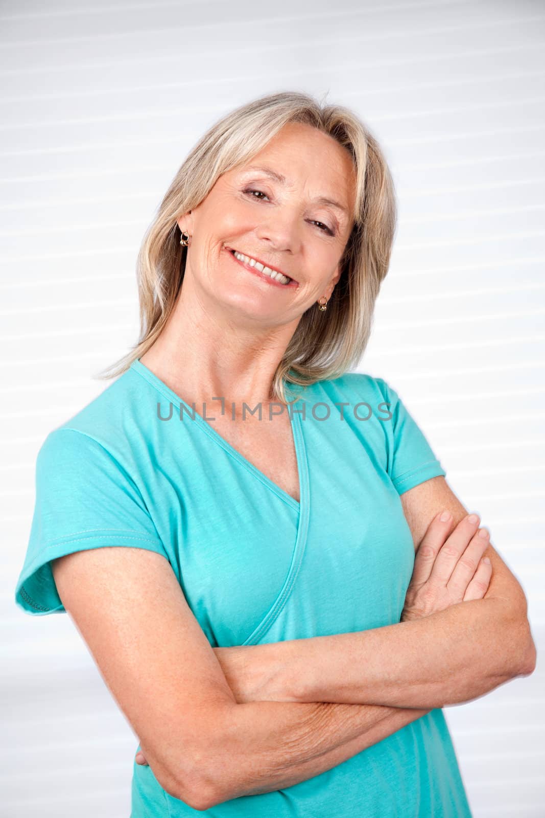 Portrait of cheerful mature woman with arms crossed standing against white background