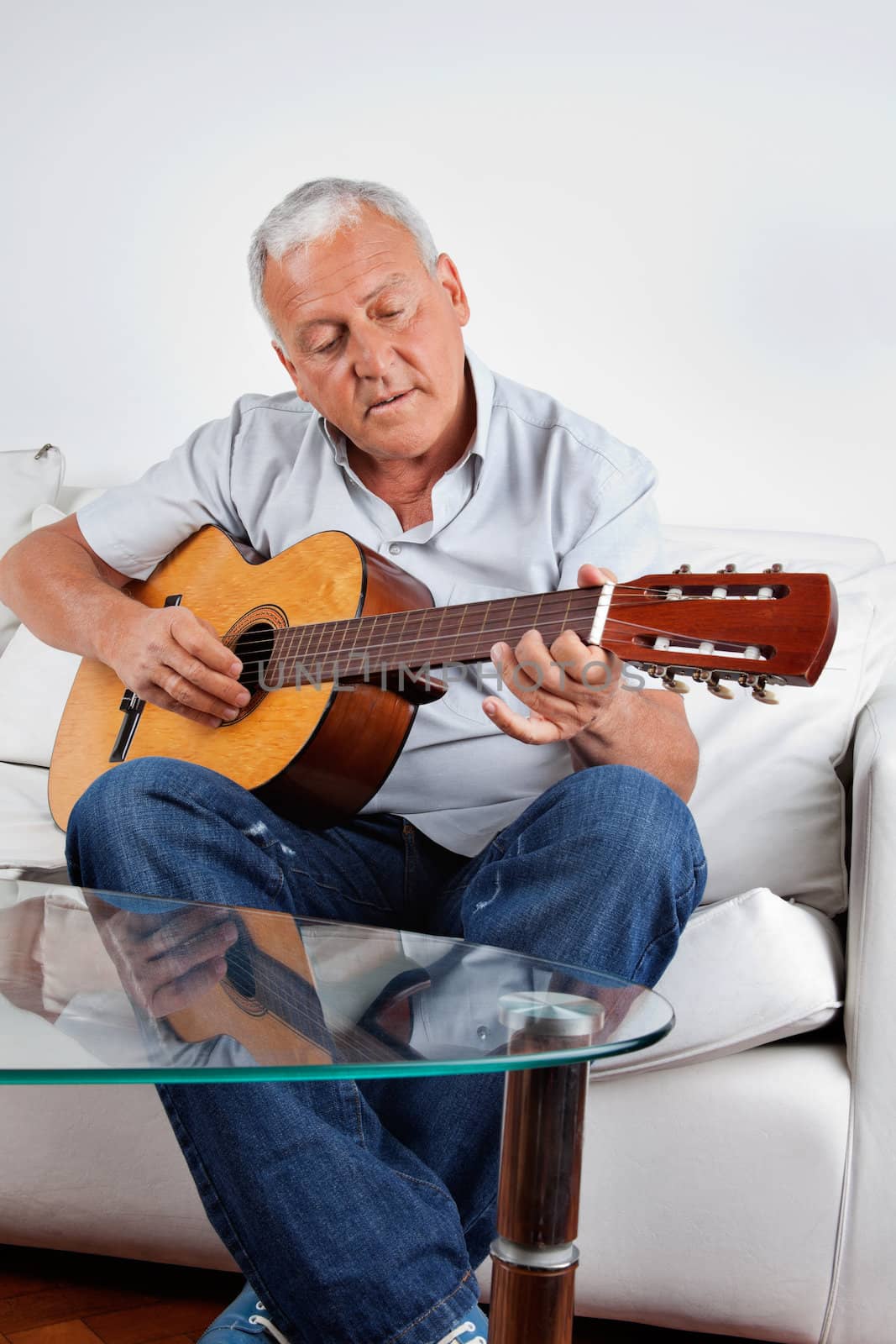 Senior man playing acoustic guitar at home