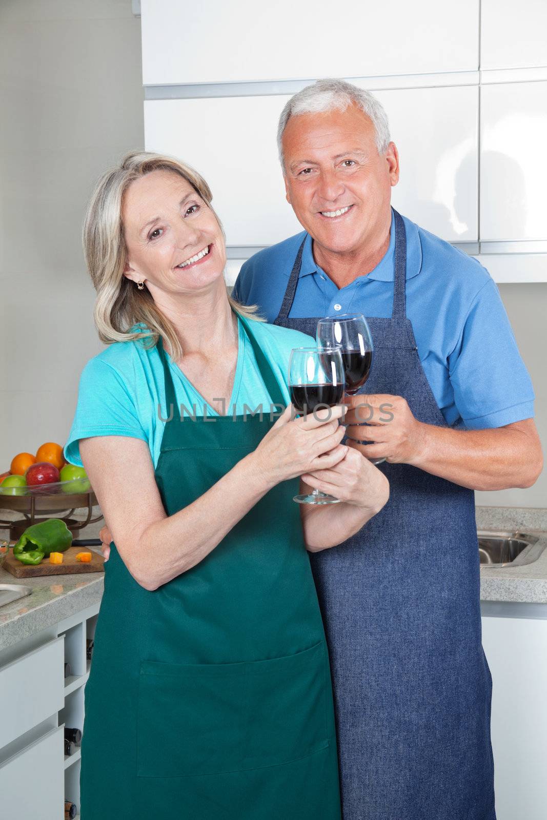 Portrait of smiling couple toasting wine glasses in the kitchen