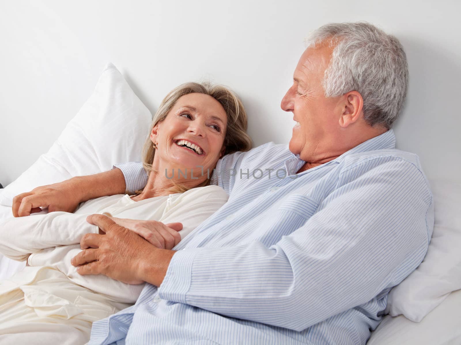 Cheerful couple relaxing on bed at home