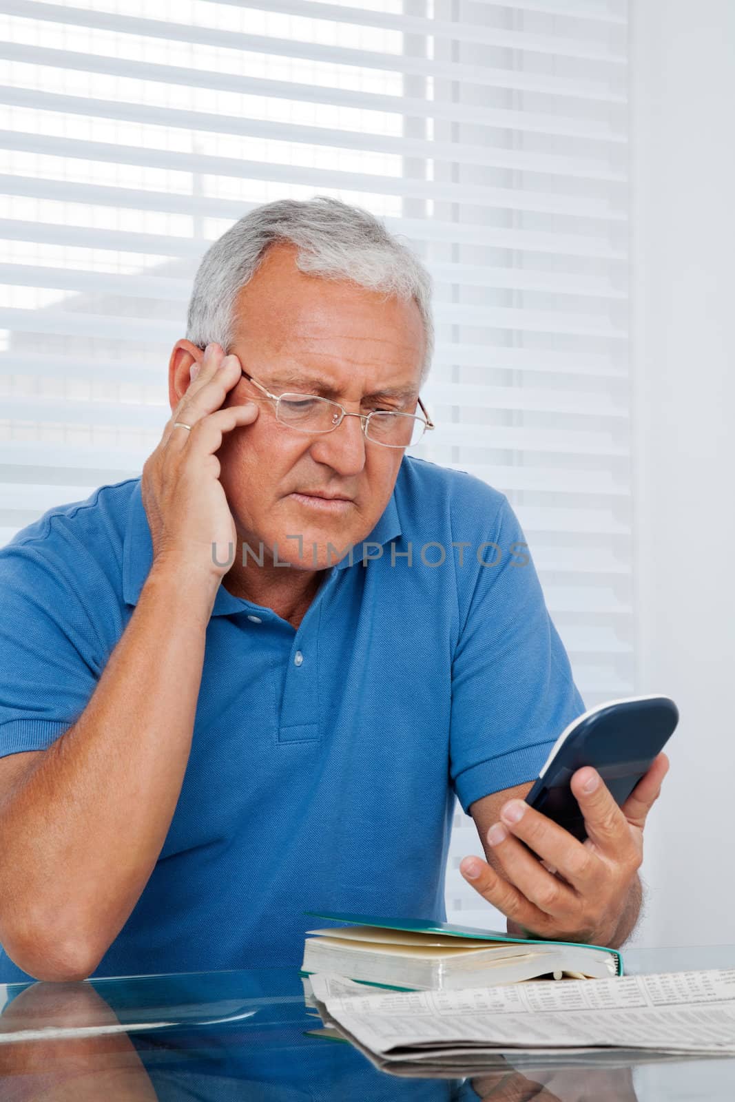 Serious senior man looking at calculator